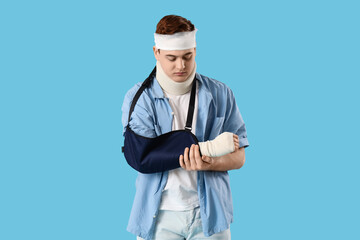 Injured young man after accident with broken arm on blue background