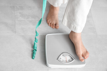 Young woman going to measure her weight at home. Diet concept