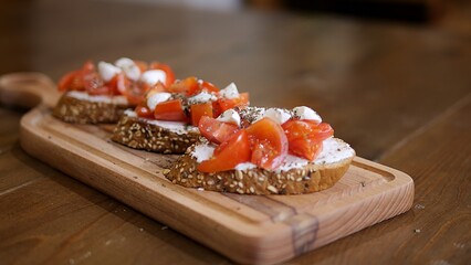 A woman's hand touches a sandwich with creamy cheese and tomatoes. Fresh tomatoes adorn the creamy cheese spread on the sandwich. Red tomatoes add color and flavor to the creamy cheese sandwich