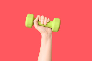 Female hand with dumbbell on red background, closeup