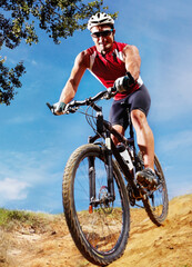 Fototapeta premium Nature, sports and man athlete with bicycle in park for marathon, race or competition training. Fitness, portrait and male cyclist riding bike for cardio workout or exercise in outdoor forest.