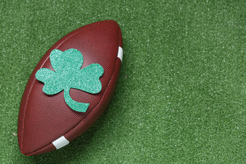 Rugby ball with clover on green grass background. St. Patrick's Day celebration