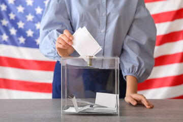 Voting young woman with USA flag near ballot box on table at polling station, closeup