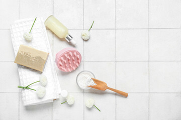 Hair scalp massager with shampoo bar, bottle of cosmetic product and bath supplies on white tile background
