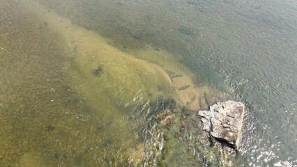 Background Looking down on clear water flowing in nature with rocks and pebbles on bottom of rivers, creeks, and streams 