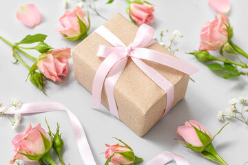 Obraz na płótnie Canvas Beautiful wrapped gift box decorated with rose flowers on light background