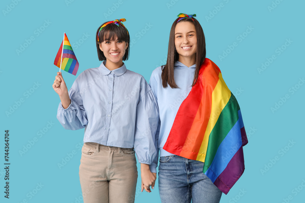 Wall mural Young lesbian couple with LGBT flags on blue background