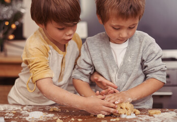 Boys, cutter and baking in kitchen with dough, home and learning to bake a christmas cake. Children, playing and shape for cookies on counter, biscuits and wheat pastry for sweet dessert on holiday