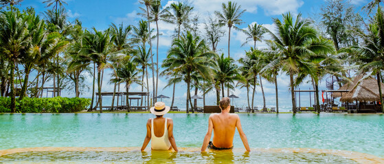 A man and a woman are lounging in a pool with palm trees all around them, enjoying the water and...