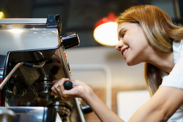 Professional Asian female barista pouring a hot milk over the espresso in coffee cup. 