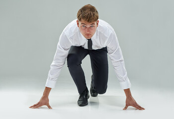 Portrait, competitive businessman and starting position on studio background to chase deadline,...