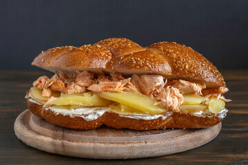 Challah sandwich with grilled salmon, boiled potato and cream cheese on dark background. Israeli food.