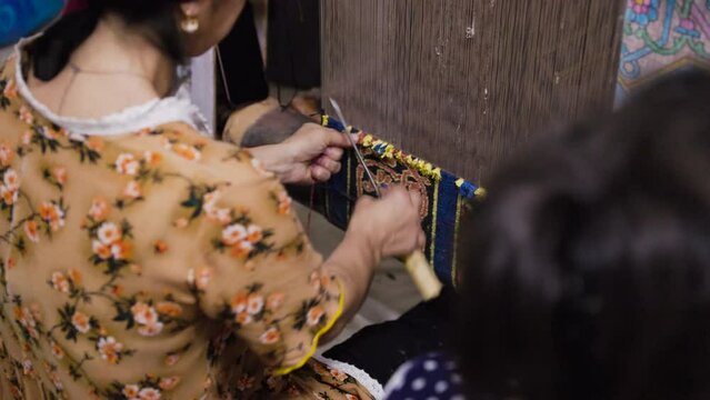 Uzbek woman making traditional carpet in the workshop.