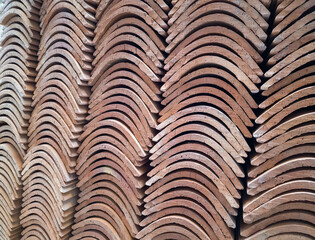 Vintage red roof tiles, stacked and arched, made of terracotta, ceramic or clay - abstract pattern.