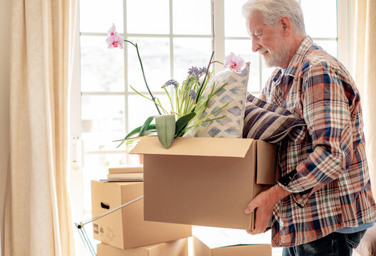 Hipster smiling senior man involved in moving house moving cardboard boxes, concept of relocation, retirement, new life, buying, renting, apartment, house