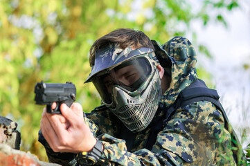 military man with a pistol in his hands, in camouflage uniform, protective mask and goggles
