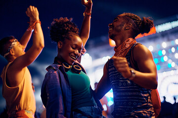 Black carefree couple dancing and having fun on summer music festival at night.