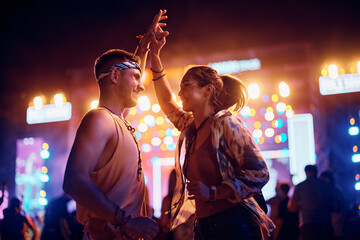 Young happy couple dancing on summer music festival at night.