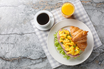Scrambled egg sandwich with ham, green onions and lettuce served with orange juice and coffee...