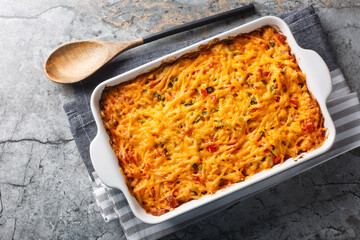 King Ranch Casserole is classic Texas comfort food with vegetables, cheddar cheese, tortilla and cream close-up in a baking dish on a marble table. Horizontal top view from above