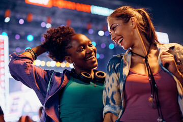 Young happy women having fun while dancing during open air music concert at night.