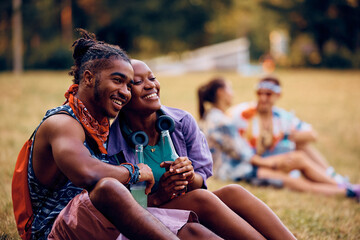 Happy black couple relaxing while waiting for open air music concert to begin.