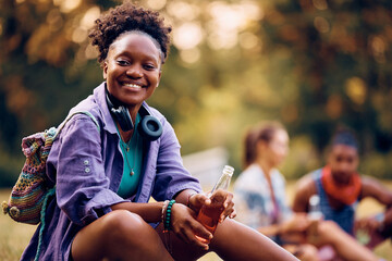 Happy black woman enjoying during summer music festival in park and looking at camera.