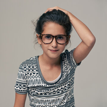Portrait, fashion and glasses with girl child in studio isolated on gray background for optometry style. Kids, frame lens or eyewear with cute young geek or nerd in clothes outfit and accessories
