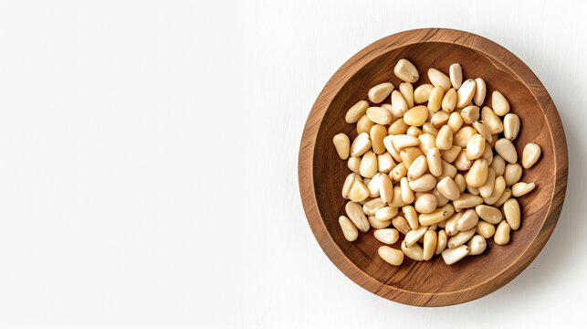 Pine nuts in a wooden plate on a white background.