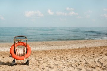 Life buoy ring in a cart on a sandy beach shore on a summer day
