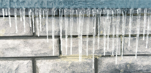 Icicles hang from the brick wall of the building