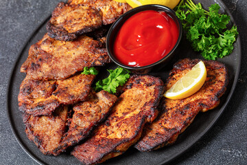 fried juicy pork steaks with ketchup on plate