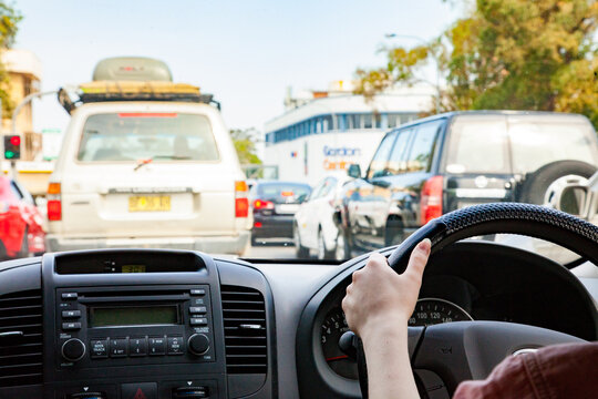 Teen driver driving in city traffic with hands on car steering wheel