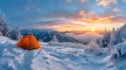 Fotobehang An orange tent pitched on a snow-covered mountain peak with the sun rising above the clouds and mountains in the background. © wcirco