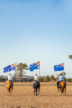 Australian stock horse riders holding flags while Advance Australia Fair national anthem is played