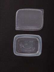 Empty plastic disposable food container, transparent lid isolated on black background.