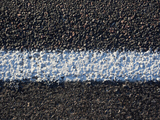 White markings on dark asphalt close-up