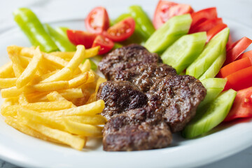 Traditional Turkish meatballs served with French fries tomatoes . High quality photo