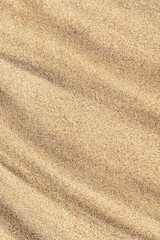 Fototapeta na wymiar Vertical wavy sand texture close-up. Sandy beach background. Summer, vacation, relax backdrop, top view.