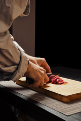 Closeup of hands of woman slicing raw beef meat on thin slices