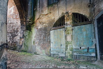 Vieille ruelle pavée médiévale sous une arche. Ancienne rue de Semur-en-Auxois. Rue historique. Vieille porte rustique bleue. Mur décrépi. 