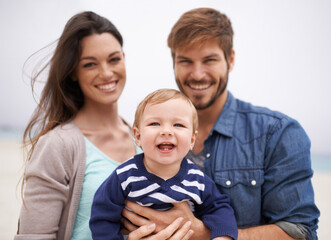Obraz premium Mother, father and portrait with toddler at beach for family, love and adventure together on vacation. Happy, man and woman with baby by ocean for support, travel and relaxing holiday in Los Angeles