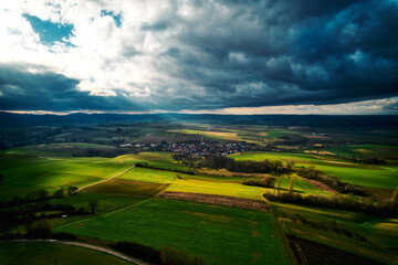 Fototapeta na wymiar Aerial view of green fields under a dramatic cloudy sky