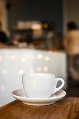 A white cup of black coffee on a saucer on the wooden table in a cafe - 744462778