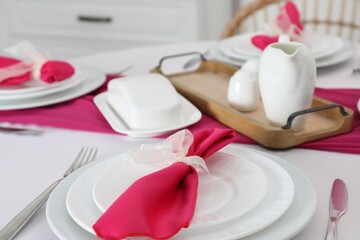 Color accent table setting. Plates, cutlery and pink napkin, closeup