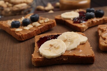 Different tasty toasts with nut butter and products on table, closeup