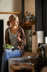 Thinking, woman and eating salad in kitchen at home, nutrition and fresh leafy greens for healthy...