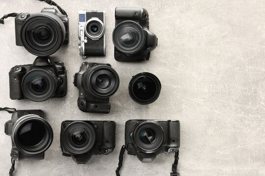 Modern cameras on gray textured table, flat lay. Space for text