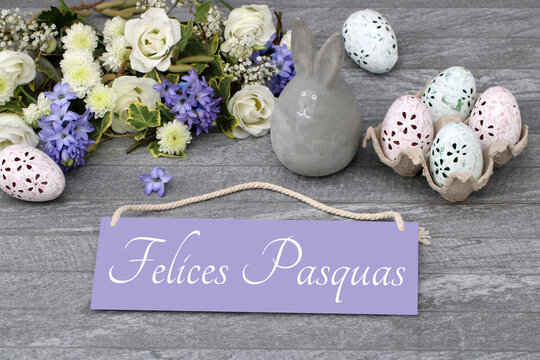 El texto Felices Pascuas escrito en un cartel con adornos y flores de Pascua.