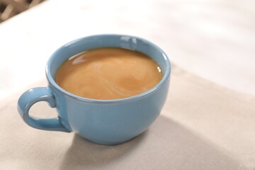 Delicious coffee in cup on white table, closeup. Space for text